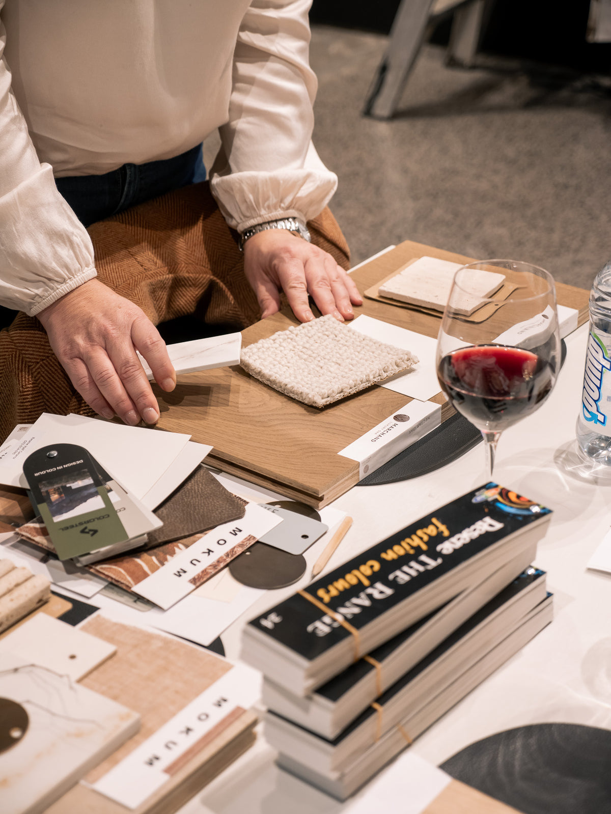 Design consultation in the Marchand studio: a designer laying oak sample boards into a flatlay of stone, tile and textile swatches on the table