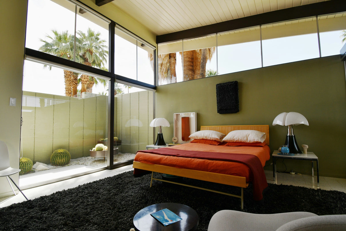 Single-storey mid-century bedroom with timber ceiling and full-height glazing. Reference photograph by Max Harlynking via Unsplash